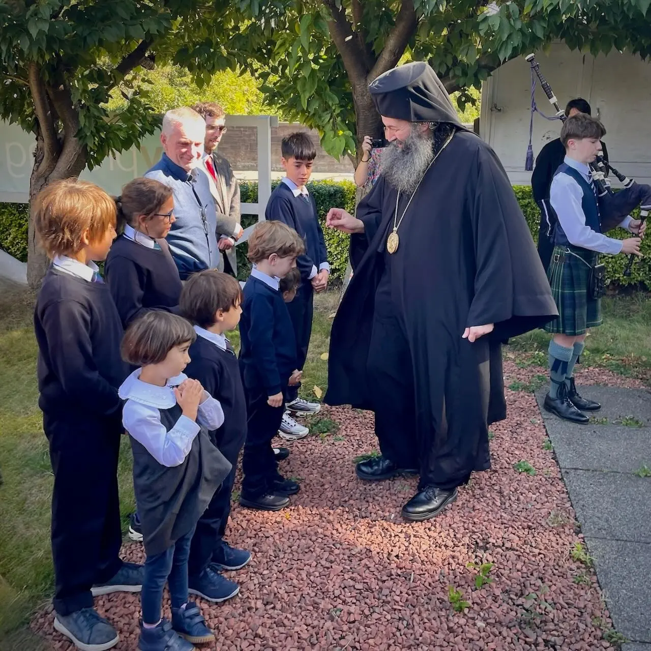 The children welcome Bishop Raphael with the sound of bagpipes